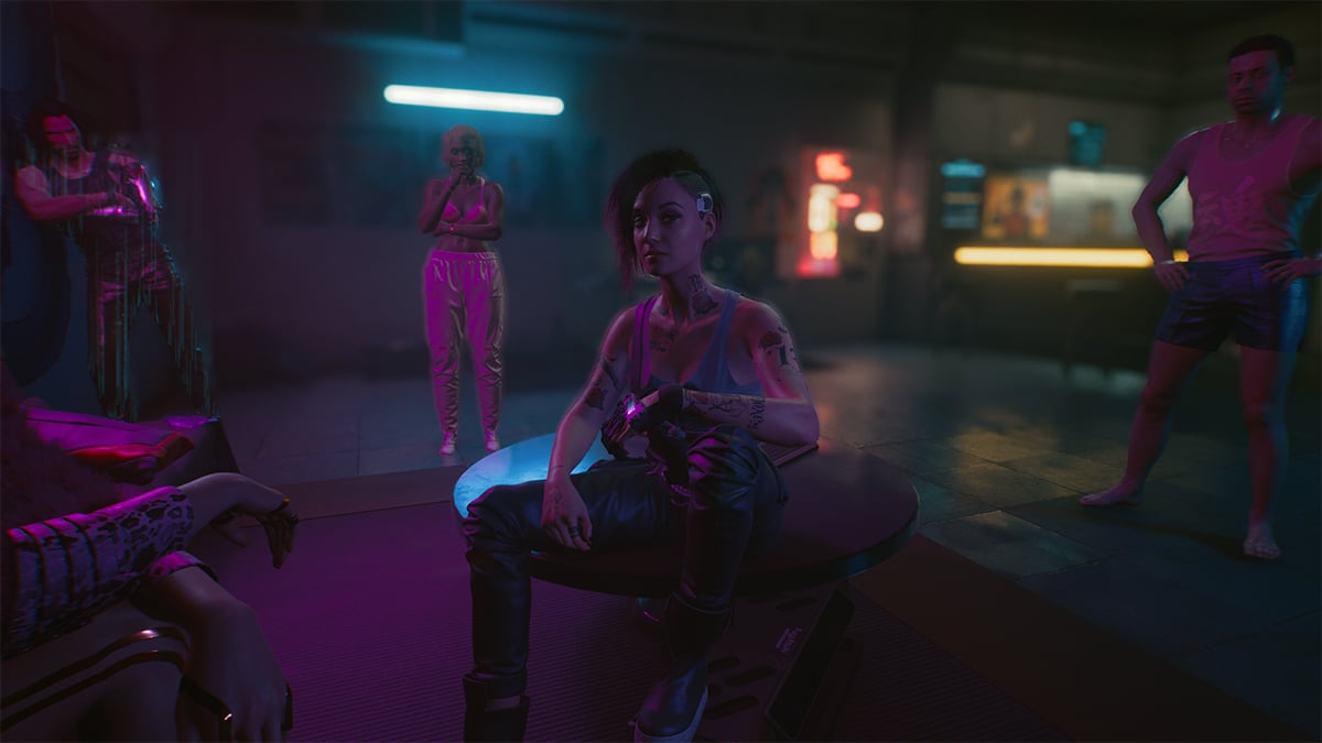 Judy, sitting on the living room round table in her apartment, talking to V with Johnny Silverhand and Judy's friends hanging in the background