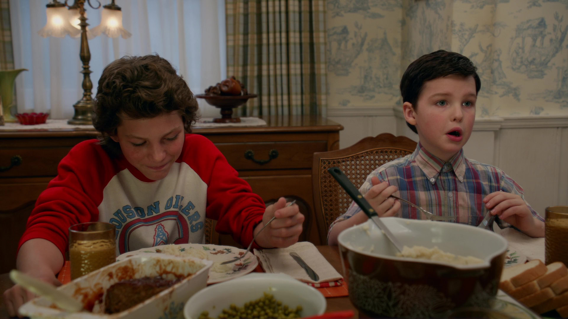 Young Sheldon and his brother having dinner