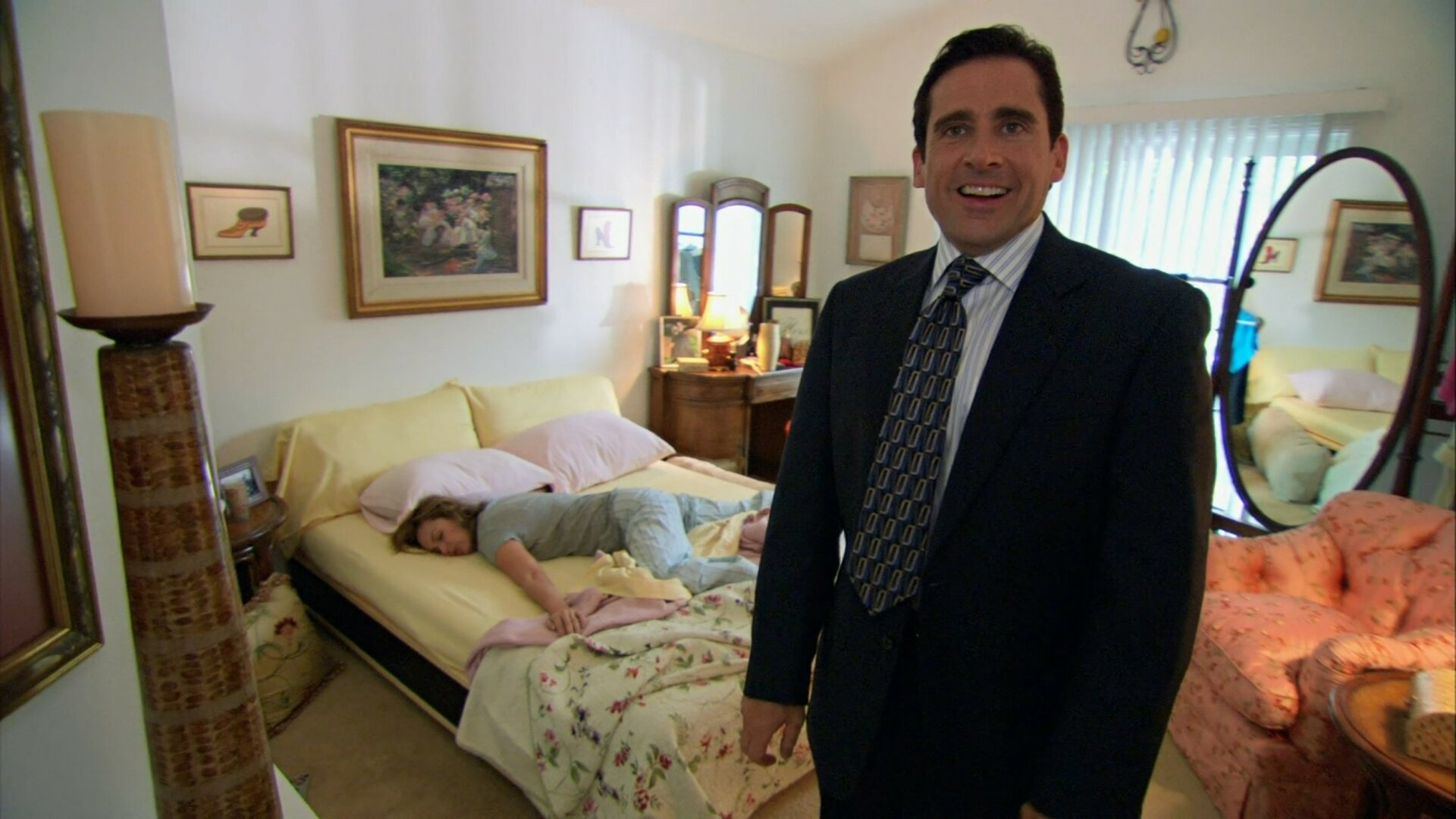 A scene from The Office where Michael is staring at the camera and Jan is on the bed sleeping